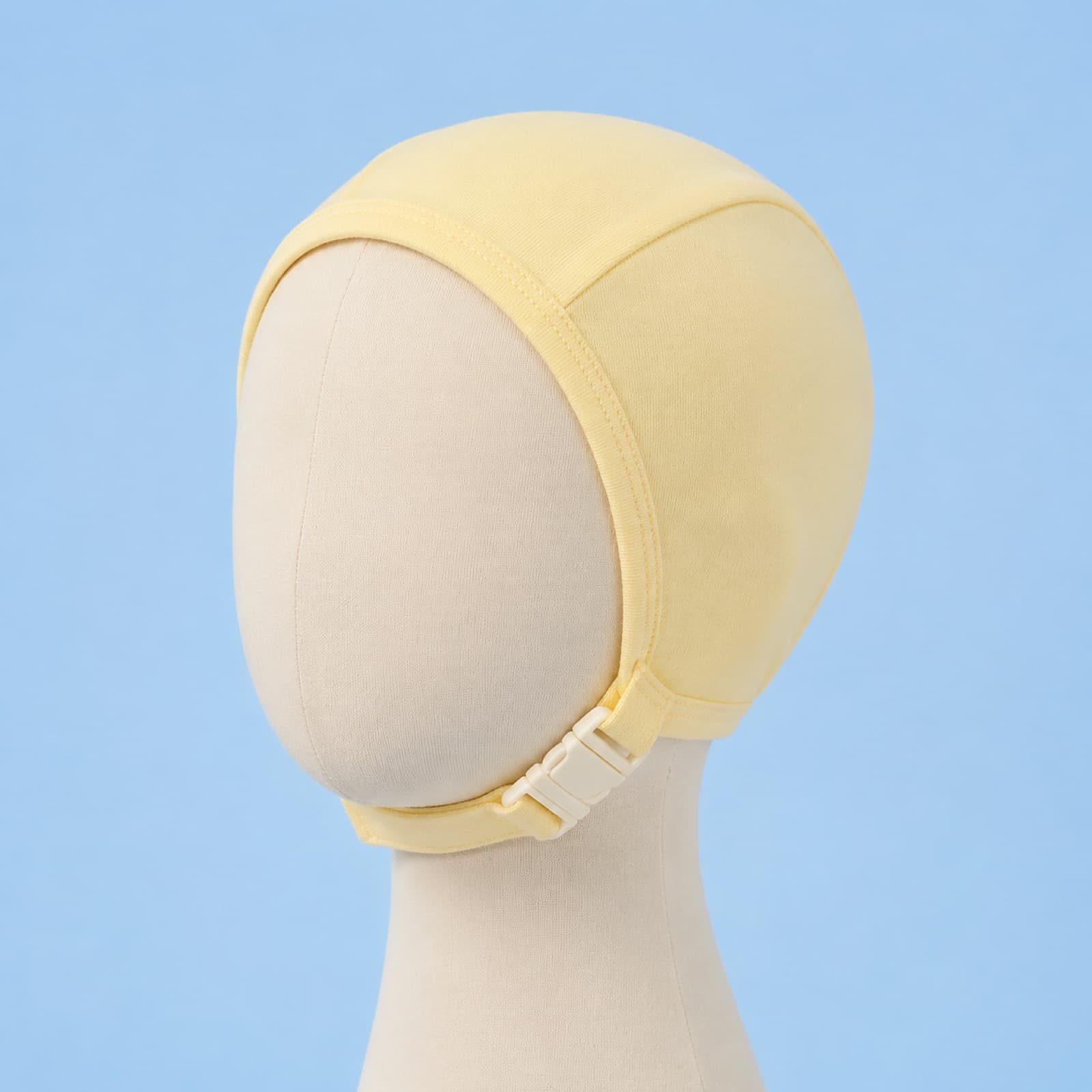 Butter-yellow cotton baby bonnet on a plain head form